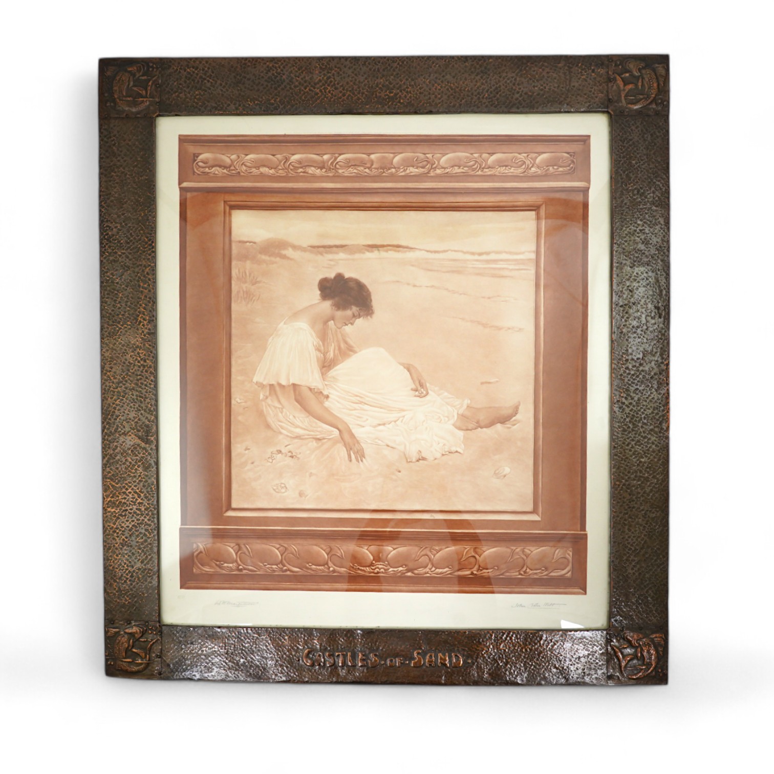 An Arts & Crafts large planished copper picture frame with fish motif to each corner, and with raised lettering 'Castles of Sand', inset with a mezzotint in sepia of Castles of Sand by William Henry Margetson (1861-1940)